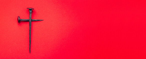 Cross made with rusty nails and drops of blood on red background. Copy space. Good Friday, Easter...