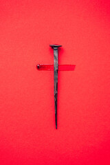 Christian cross made with rusty nails, drops of blood on red background. Copy space. Good Friday,...