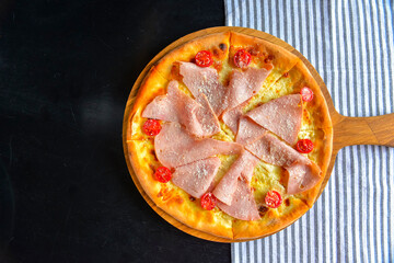 Pizza with bacon, salami and vegetables. Ham and tomatoes pizza with melted cheese.