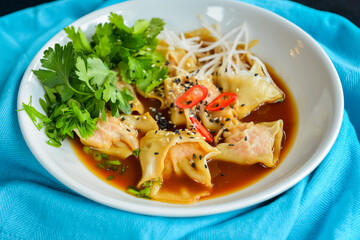 Boiled meat dumplings with fresh parsley, soy sauce and sesame seeds. Delicious meal for dinner.
