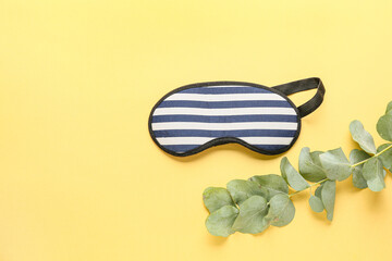 Sleep mask and eucalyptus branch on color background