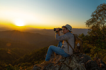 Adventurous man with binoculars standing in the forest