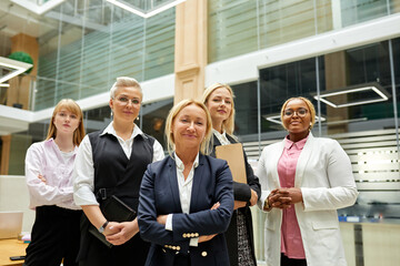 portrait of confident team of business ladies in formal wear, team in the head of adult female director posing at camera with folded arms