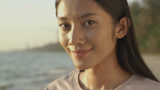 Portrait of beautiful woman at sea background. Close-up beautiful woman face, She looking to camera with attractive smile.