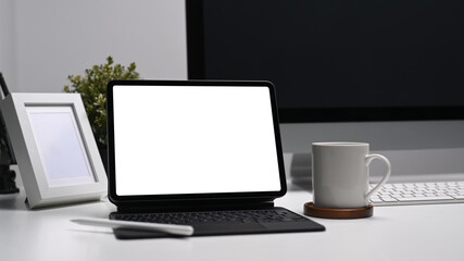 Fototapeta premium Modern work place with blank screen computer tablet, coffee cup and frame on white table.