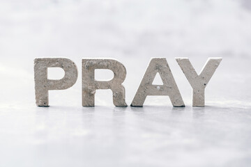 Word PRAY made with cement letters on grey marble background. Copy space. Biblical, spiritual or...