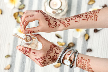 Beautiful female hands with henna tattoo and reed diffuser, top view
