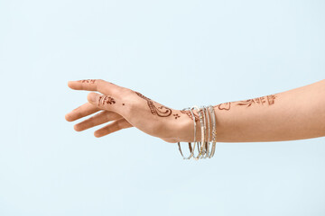 Beautiful female hand with henna tattoo on light background