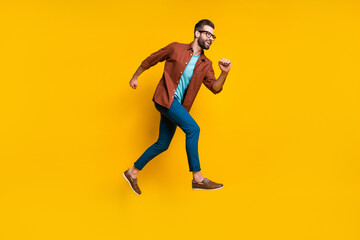 Fototapeta na wymiar Full length body size photo of man running fast on sale jumping isolated on vivid yellow color background