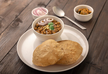 Spicy chick peas curry or Chana Masala or choley with fried puri garnished with sliced onion and green coriander leaf