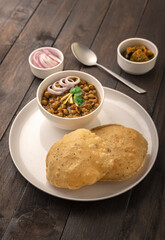 Spicy chick peas curry or Chana Masala or choley with fried puri garnished with sliced onion and green coriander leaf