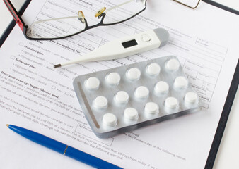 Clipboard, eyeglasses, pills, termometr and blue pen. Top view, copy space.