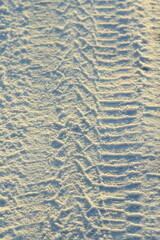 Tire tracks left in the snow on a bright sunny day