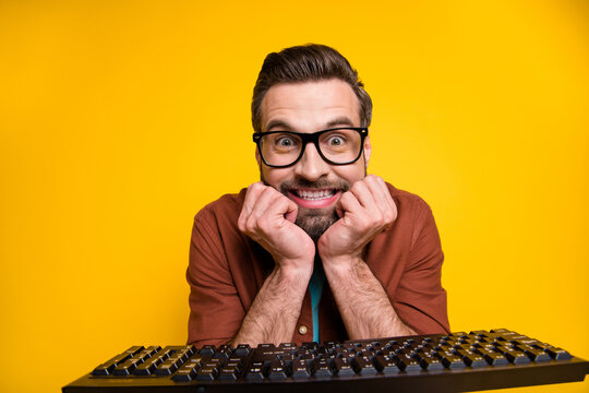 Photo portrait of bearded man staring mad crazy nerd programmer with keyboard eyewear isolated on vivid yellow color background