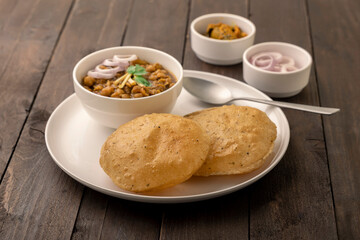 Spicy chick peas curry or Chana Masala or choley with fried puri garnished with sliced onion and green coriander leaf