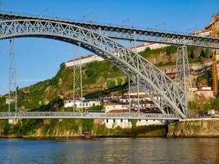 Naklejka premium Ponte Luis bridge in Porto as a rabelo boat passes underneath