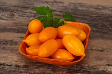 Yellow tomato heap in the wooden bowl
