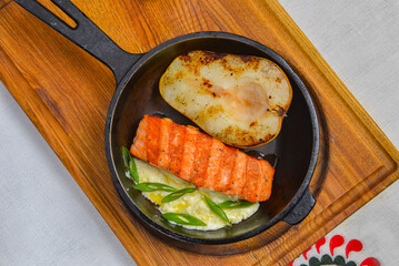 Fototapeta na wymiar Salmon steak grilled with half a pear served in a pan over wooden board. Ukrainian cuisine concept.