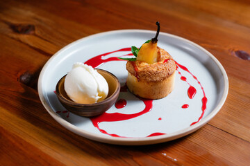 Dessert with pear and ice cream garnished with fruit sauce side view.