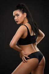 Fototapeta na wymiar beautiful brunette girl in black sportswear posing on a black background