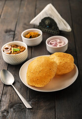 Spicy chick peas curry or Chana Masala or choley with fried puri garnished with sliced onion and green coriander leaf