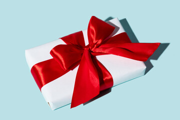 Romantic gift. Valentine day. Special day surprise. Holiday congratulation. Present wrapped in white box with red ribbon bow isolated on blue background.