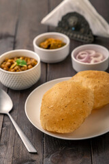 Spicy chick peas curry or Chana Masala or choley with fried puri garnished with sliced onion and green coriander leaf