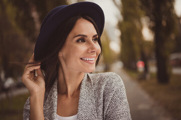 Photo portrait of smiling woman wearing hat walking in city park windy weather in fall