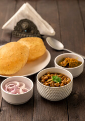 Spicy chick peas curry or Chana Masala or choley with fried puri garnished with sliced onion and green coriander leaf