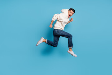 Fototapeta na wymiar Full size profile side photo of young happy excited smiling positive man running jumping isolated on blue color background