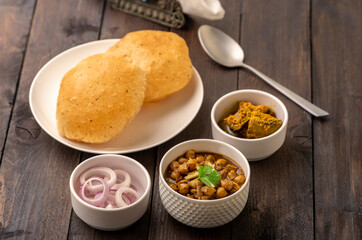 Spicy chick peas curry or Chana Masala or choley with fried puri garnished with sliced onion and green coriander leaf