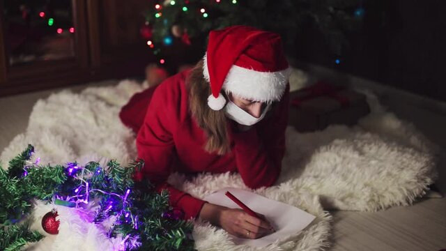 a woman in red clothes is sitting waiting for the new year. the concept of celebrating Christmas at midnight. holiday costume. a girl writes a letter to Santa Claus. wish list