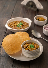 Spicy chick peas curry or Chana Masala or choley with fried puri garnished with sliced onion and green coriander leaf