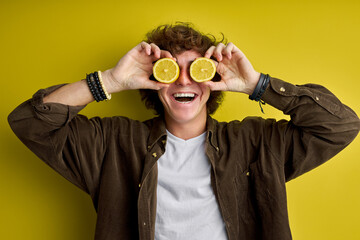 funny young man posing with lemon isolated on green background in studio, healthy fashion lifestyle, people emotions, cold season concept. cheerful guy in casual wear