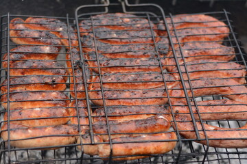 Ruddy sausages are grilled on an outdoor barbecue
