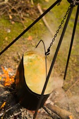 Soup is cooked over an open fire in a pot at a picnic