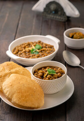 Spicy chick peas curry or Chana Masala or choley with fried puri garnished with sliced onion and green coriander leaf