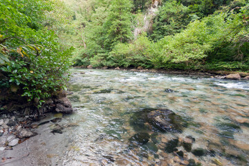 A small mountain river among the mountainous green slopes, used as a background or texture