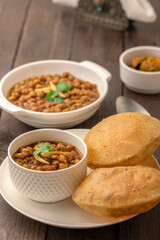 Spicy chick peas curry or Chana Masala or choley with fried puri garnished with sliced onion and green coriander leaf