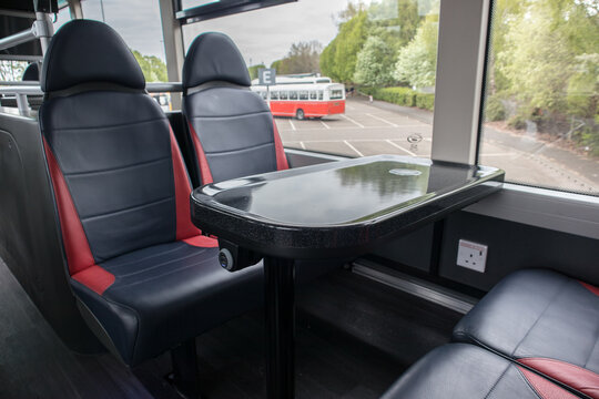 Inside interior of modern bus double decker bus showing seating and table with aircharging mobile phone charging point.