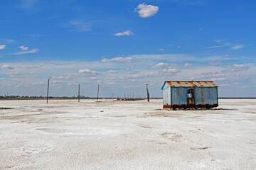 Abandoned old blue metal house on the background of pillars at salt lake Baskunchak