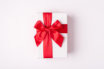 Top overhead close up view photo of rectangular present box tie with red light ribbon and bow isolated white color background