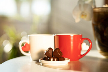 Two cups of coffee or tea with heart-shaped chocolates. Red and white. Happy Valentine’s Day and love concept. Background of romantic mood. Wedding day. Selective focus.