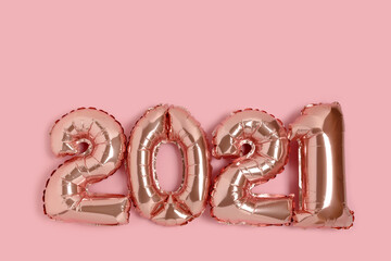 2021 made from rose gold color balloons on a pink background with copy space.