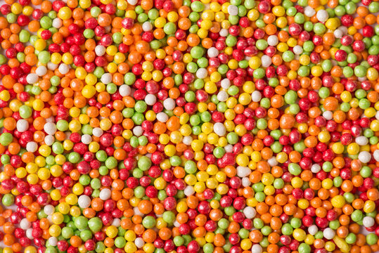 Close up photo of bright background made of rainbow sugar sprinkle balls for cupcakes
