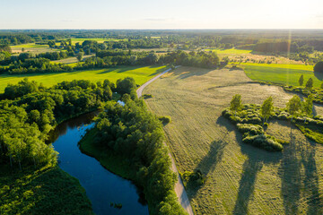 aerial view of Latvian rural landscape with a winding river, forests and country roads at sunset