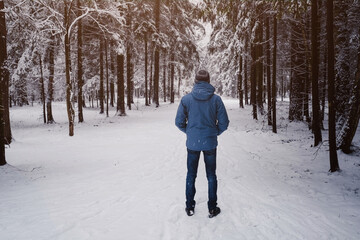 A man breathes deeply in the calm winter forest on a cold day.