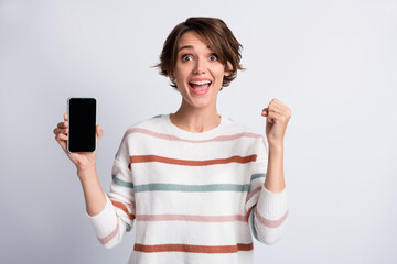 Photo of funny impressed woman dressed striped pullover holding modern device rising fist isolated grey color background