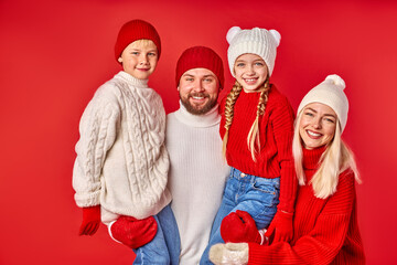 portrait of cheerful family with kids posing isolated in studio with red wall background, young parents and children celebrating holidays