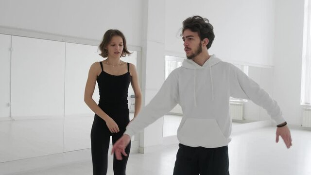 Young beautiful couple studying ballroom dance. A professional ballroom dancing couple dances in a large, bright, white hall